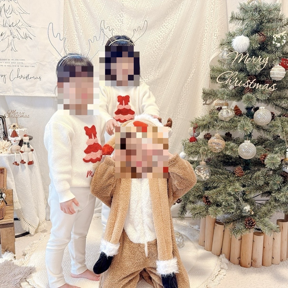 クリスマスツリーと白い背景布の前で、トナカイの角カチューシャをつけて撮った子どもたちのクリスマスフォト