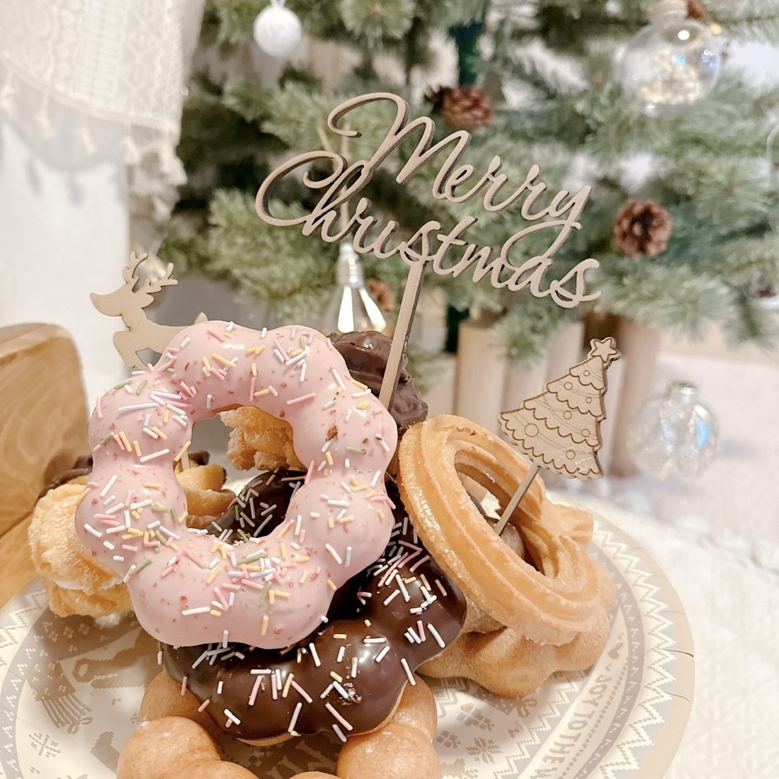 ドーナツを重ねて作ったクリスマスケーキ。木製のMerry Christmasケーキトッパーとトナカイ・ツリーのピックを飾っている