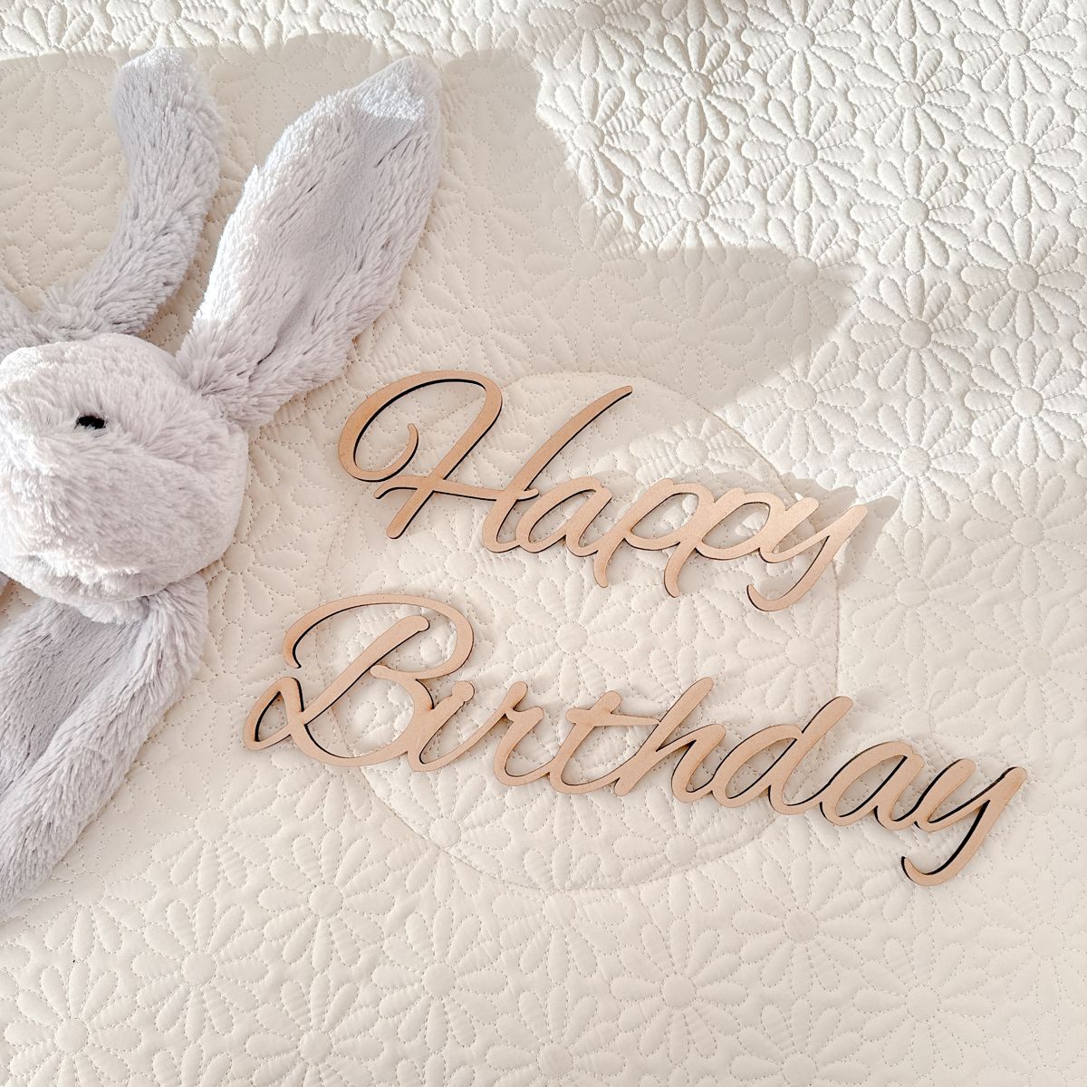 Happy Birthdayの木製レターバナーと、グレーのうさぎのぬいぐるみ