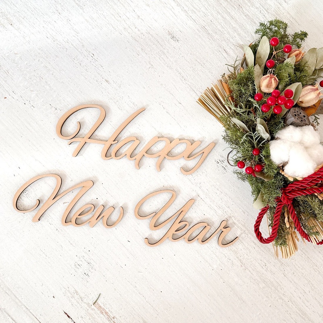 木製のHappy New Yearレターバナーとお正月のドライフラワー飾りを並べた撮影用の飾り付け