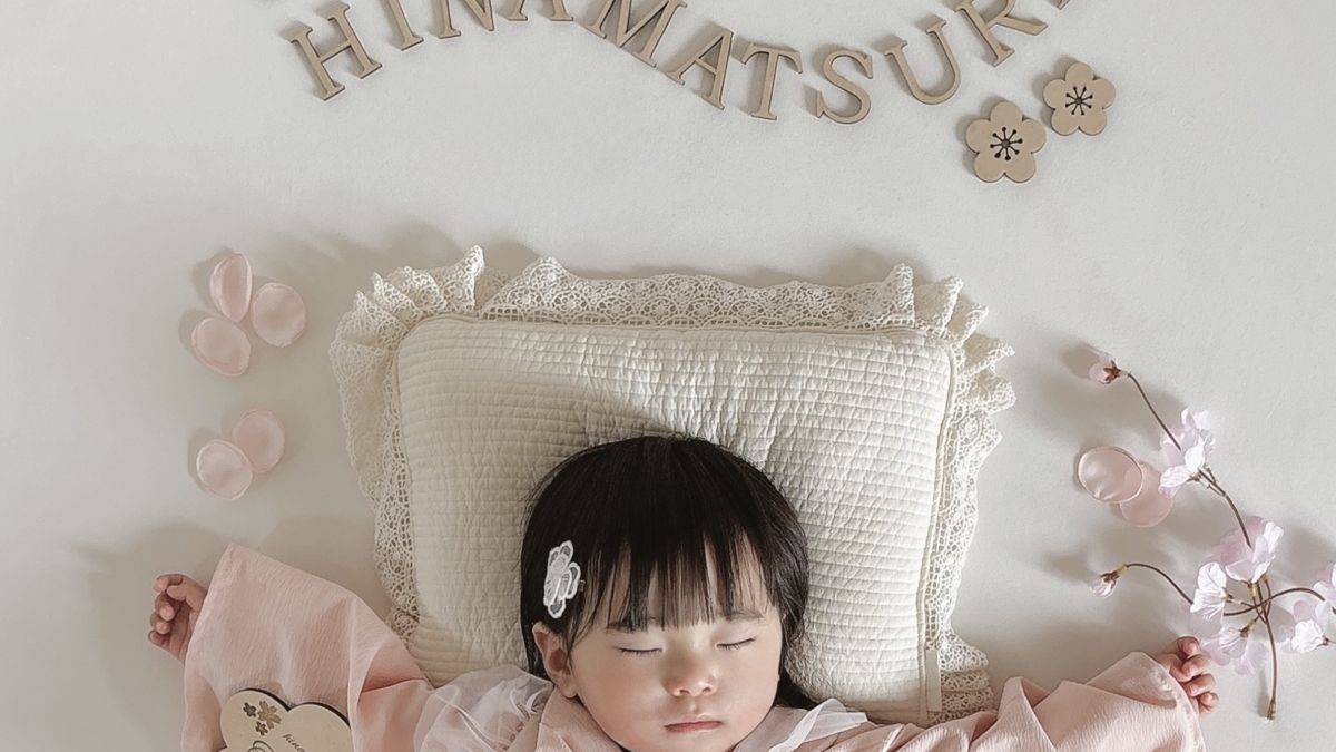 桜とHINAMATSURIの飾りに囲まれて眠る赤ちゃん。初節句のおうちフォト