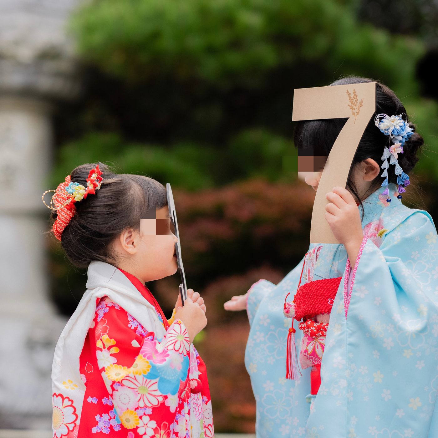 赤い着物に赤い髪飾りをつけた3歳の女の子。プロのヘアセットで短い髪もふんわり可愛く