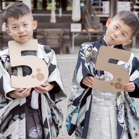 羽織袴すがたの男の子ふたりが木製の「5」プレートを持って並ぶ様子